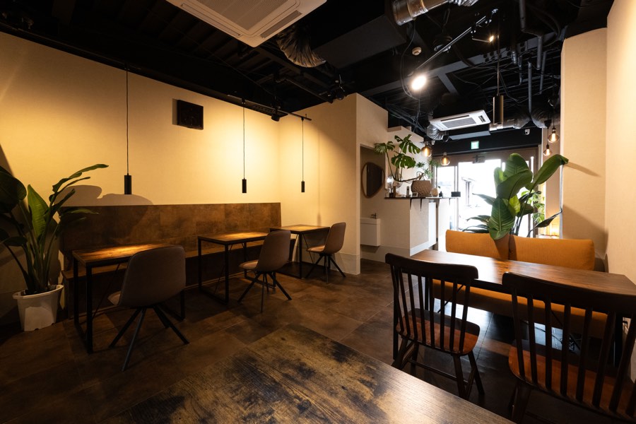 店内。テーブルとソファ、窓辺の植物